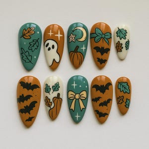 Puede incluir: Un conjunto de diez uñas postizas en forma de almendra con temática de Halloween. Los diseños incluyen murciélagos, fantasmas, calabazas, hojas, lazos y cruces. Las uñas presentan una paleta de colores: verde azulado, naranja, blanco y negro.