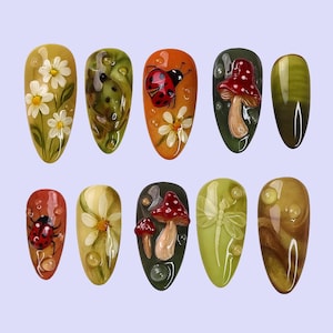 May include: A set of ten oval-shaped artificial nails with nature-themed designs. The designs include daisies, ladybugs, mushrooms, and a dragonfly, in shades of green, orange, and yellow. The nails have a glossy finish.