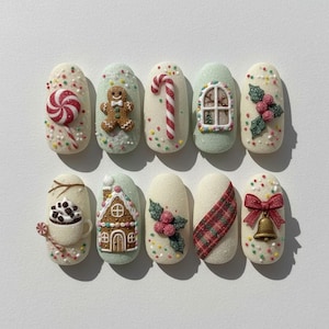 Puede incluir: Un conjunto de diez diseños de uñas con temática navideña. Cada uña presenta un diseño festivo diferente, que incluye un bastón de caramelo, un hombre de jengibre y una casa de jengibre. Las uñas están decoradas con chispas y purpurina de colores.
