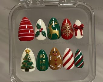 May include: A set of ten artificial nails with festive Christmas designs. The nails feature red and white stripes, a gold reindeer, a snowflake, a bow, a Christmas tree, a gingerbread man, and the text "HO HO HO".