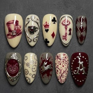 Puede incluir: Un conjunto de diez uñas pintadas en forma de almendra con el tema de "Alicia en el país de las maravillas". Los diseños incluyen un sombrero de copa, palos de cartas, una llave, un gato de Cheshire y un conejo. Colores: crema, burdeos, plata y gris.