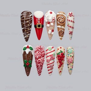 May include: A collection of ten long, almond-shaped artificial nails with festive Christmas designs. The nails feature various decorations, including candy canes, gingerbread, Santa Claus, and other holiday-themed embellishments. The color palette includes red, white, brown, and gold.