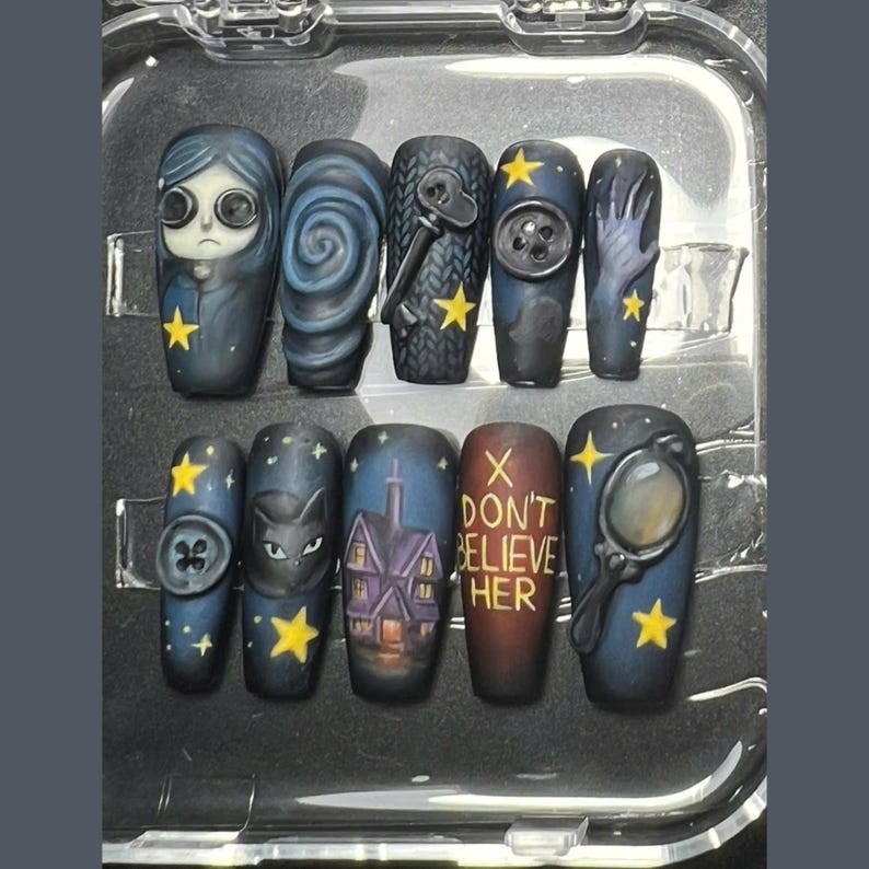 May include: A set of ten press-on nails with a dark, whimsical theme. Each nail features unique artwork, including a character, swirling patterns, a key, a button, a hand, a cat, a house, text that reads "DON'T BELIEVE HER", and a magnifying glass.