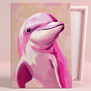 May include: A pink dolphin portrait on canvas. The artwork features a close-up of the dolphin's head and upper body, rendered in shades of pink and white against a light beige background. The canvas is stretched over a wooden frame.