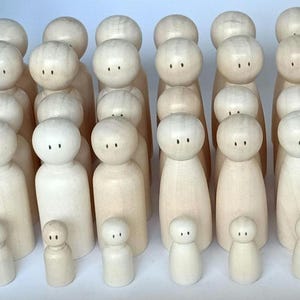 May include: A group of 25 wooden peg dolls in various sizes, all painted in a natural wood colour. The dolls are arranged in rows, with the largest dolls at the back and the smallest dolls at the front.