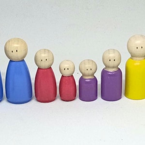 Puede incluir: Un conjunto de ocho muñecos de madera con clavijas pintadas en varios colores, incluyendo azul, rojo, morado y amarillo. Los muñecos están ordenados por tamaño, con el muñeco más pequeño en la parte delantera y el más grande en la parte trasera. El muñeco más pequeño tiene el número "1" escrito en él.