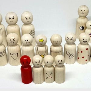 Puede incluir: Una colección de 14 muñecos de madera con diferentes caras y diseños pintados. Los muñecos están todos de pie sobre una superficie blanca. Algunos de los muñecos tienen expresiones faciales pintadas, mientras que otros tienen diseños como una corona, una espada y una barba.