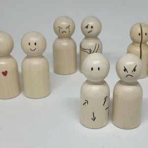 May include: A set of nine wooden peg dolls with different facial expressions, including happy, sad, angry, and confused. The dolls are all painted white and have black details.