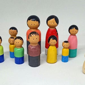 Op de afbeelding: Een verzameling beschilderde houten peg dolls in verschillende kleuren. De poppen hebben eenvoudige gezichtskenmerken en zijn gekleed in outfits van rood, geel, groen, blauw, roze en bruin. Eén pop is genummerd met het nummer 1.