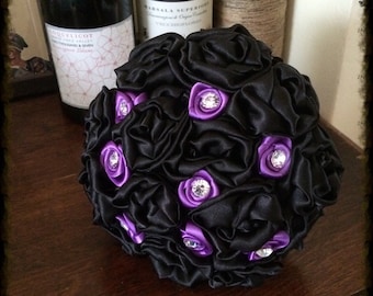 May include: A black satin flower bouquet with purple satin rosettes and rhinestone accents.