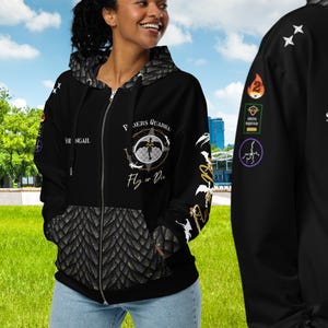May include: A black zip-up hoodie featuring a textured scale pattern on the hood and lower front. The chest displays a circular emblem with the text Riders Quadra and Fly or Die. The sleeves and back include various patches and the text Sorrengail.