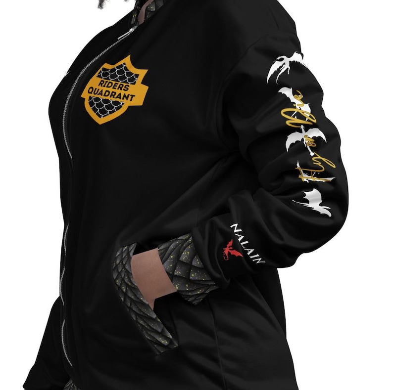 May include: A black zip-up bomber jacket featuring a yellow shield emblem on the chest with the text RIDERS QUADRANT. The sleeve displays white dragon silhouettes and the text Fly or Die, with NALAIN and a red dragon icon near the cuff.