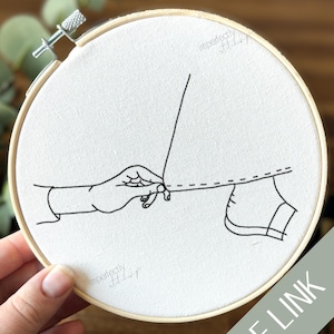 Puede incluir: Un bastidor de bordado con tela blanca y un dibujo lineal negro de una mano cosiendo. El texto "PDF LINK" está en una pancarta diagonal. Las palabras "imperfectly stitched" están impresas en la tela.