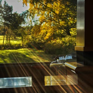 Warm golden hour sunlight streaming through a window, highlighting a glass candle cloche for cozy home decor.