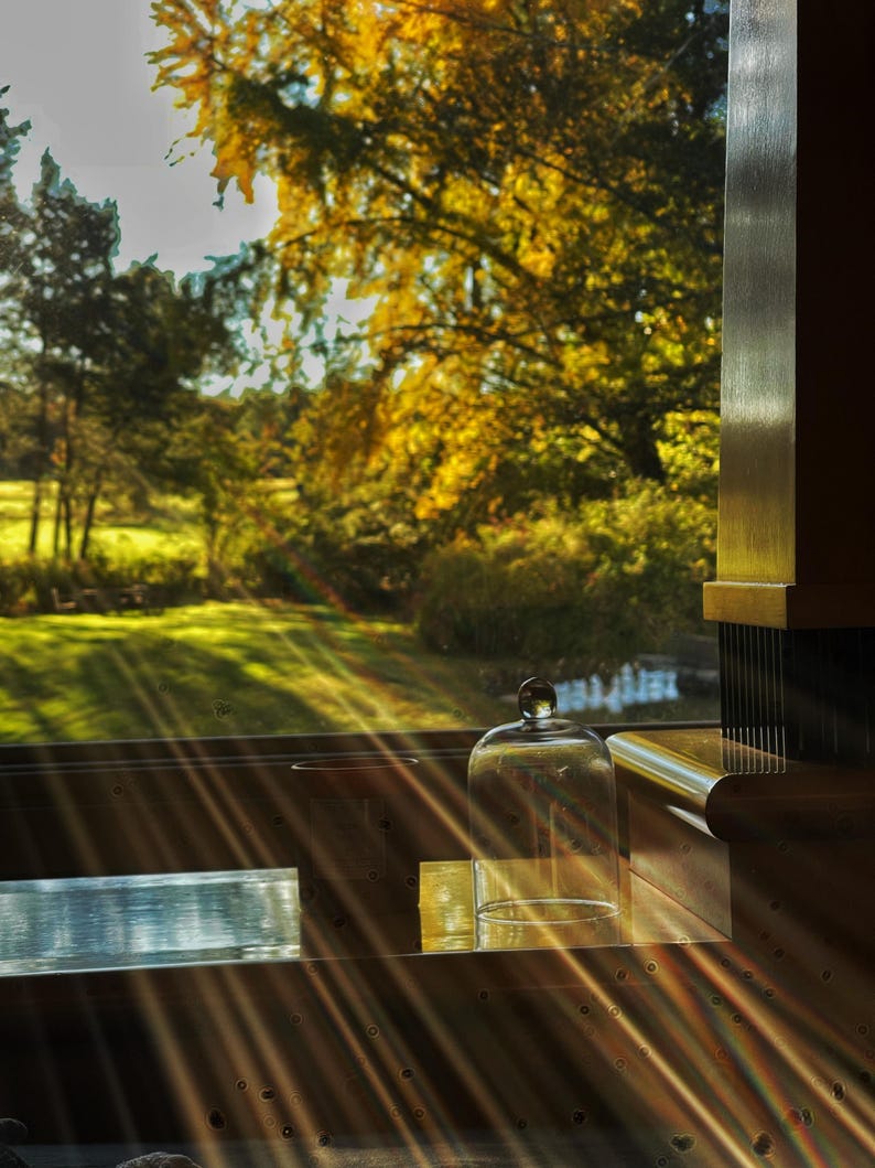 Warm golden hour sunlight streaming through a window, highlighting a glass candle cloche for cozy home decor.