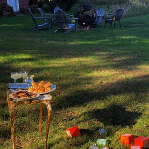Cozy outdoor garden aesthetic at golden hour, showcasing KEA ATELIER premium candles and orange luxury gift boxes on the grass.