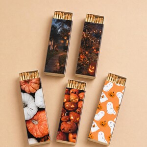 May include: Five rectangular matchboxes with sliding trays containing wooden matches. The boxes feature various Halloween-themed designs including a dark house scene, a pumpkin-lit garden, a pumpkin pile, carved jack-o'-lanterns, and white ghosts.