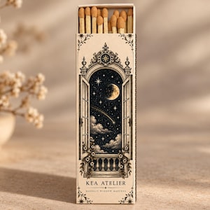 May include: A rectangular matchbox with light beige packaging featuring an illustration of an open window overlooking a night sky with a moon, stars, and clouds. The text reads KEA ATELIER MOONLIT WINDOW MATCHES. The box contains wooden matches.