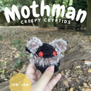 Puede incluir: Un pequeño peluche de Mothman tejido a ganchillo en color negro con detalles peludos en marrón y gris, que presenta dos ojos rojos brillantes. El texto en la imagen dice Mothman, Creepy Cryptids, low-sew y Digital PDF Download @emilybemilyscrafts.
