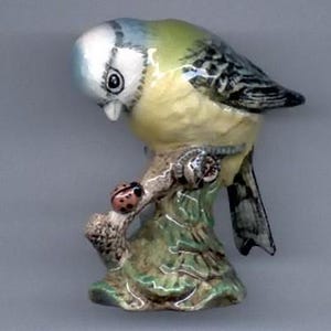 May include: A blue tit figurine perched on a branch with a ladybug. The figurine is made of ceramic and has a realistic appearance.
