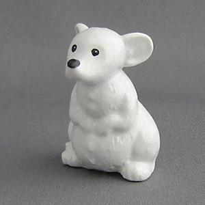May include: A white ceramic figurine of a mouse sitting on its hind legs. The mouse has black eyes and a black nose.