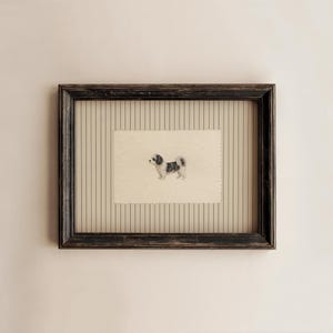 May include: A rectangular dark brown distressed wooden frame containing a cream-colored paper insert with a small illustration of a black and white dog. The background inside the frame features a vertical pinstripe pattern in tan and dark brown.