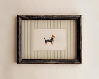 May include: A rectangular dark brown distressed wooden frame containing a cream-colored mat with thin vertical black pinstripes. Centered within the mat is a small, rectangular piece of paper featuring a detailed illustration of a Yorkshire Terrier.
