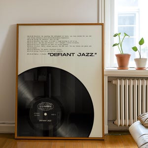 May include: A framed poster featuring a black vinyl record graphic and text from a script. The text includes dialogue lines and the phrase "DEFIANT JAZZ." The record label displays the Lumon logo, "STEREO 33 RPM," and "SIDE A." The frame is light wood.