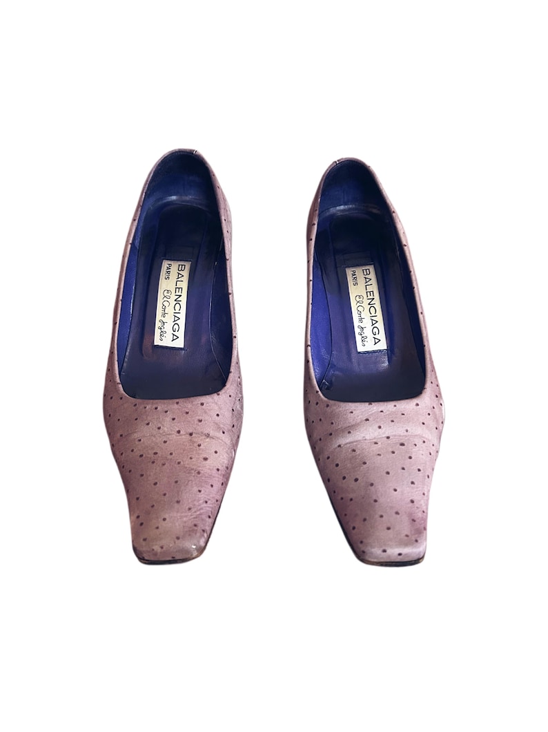 May include: A pair of light brown, square-toe pumps with small, dark brown polka dots. The shoes have a low heel and a blue interior. The brand name "BALENCIAGA PARIS El Corte Ingles" is printed inside each shoe.