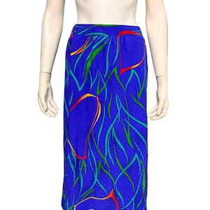 Puede incluir: Una falda azul vibrante con un diseño abstracto colorido. La falda presenta un patrón de líneas curvas verdes, naranjas y amarillas sobre un fondo punteado. La falda se muestra en un maniquí.