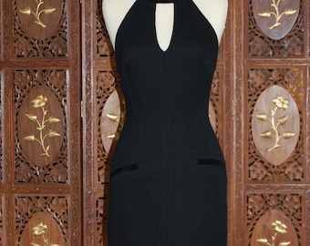 May include: A black sleeveless dress with a keyhole neckline and a fitted silhouette. The dress has a halter style strap and two pockets on the front.