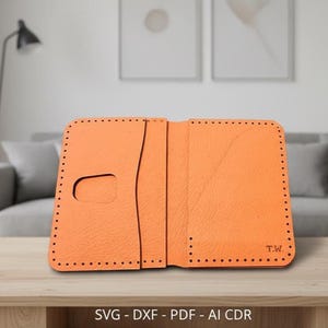 Puede incluir: Cartera de cuero naranja abierta con ranuras para tarjetas y un recorte para un teléfono. La cartera tiene un borde cosido y las iniciales "T.W." son visibles. La parte inferior de la imagen tiene el texto "SVG - DXF - PDF - AI CDR".