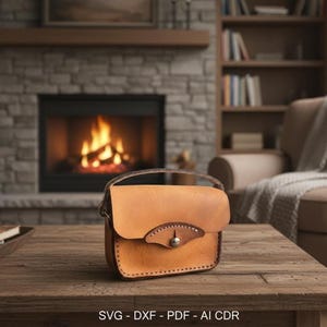 Puede incluir: Un pequeño bolso de cuero marrón claro con cierre de solapa y asa. El bolso presenta un adorno decorativo de cuero y un cierre metálico. El bolso está sobre una mesa de madera frente a una chimenea.