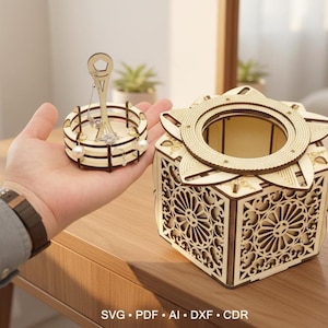 Puede incluir: Un organizador de joyas de madera y una caja a juego. El organizador tiene un diseño circular con un poste central para colgar pendientes y una base para anillos. La caja presenta intrincados patrones recortados y una tapa en forma de estrella.