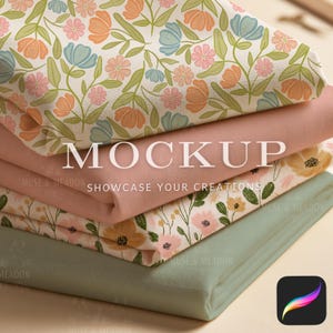 May include: A stack of four folded fabric pieces. The top piece features a floral pattern with orange, blue, and pink flowers on a white background. Below it is a solid dusty pink fabric, followed by a floral print, and a solid sage green fabric.