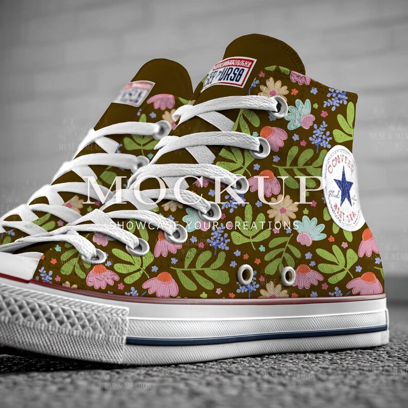 May include: High-top brown sneakers with a floral pattern featuring pink, blue, and green flowers and leaves. The sneakers have white laces, a white rubber sole, and a blue star logo on the side.