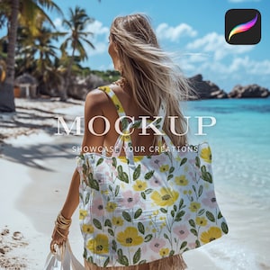 May include: A white tote bag with a floral pattern featuring yellow and pink flowers and green leaves. The bag has a long strap and is being held by a person on a beach.