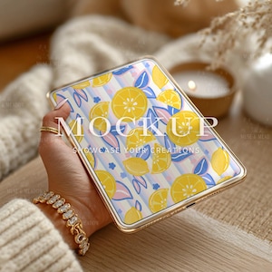 May include: A gold-framed phone case featuring a lemon pattern with yellow lemons, blue leaves, and pink accents on a striped background. The text "MOCKUP SHOWCASE YOUR CREATIONS" is displayed on the case.