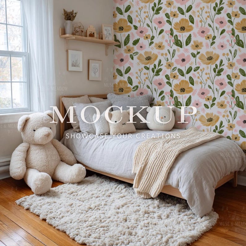 May include: A cozy bedroom scene featuring a light wood bed with gray bedding, pillows, and a cream-colored throw blanket. A large teddy bear sits on the floor next to a fluffy rug. The wall is decorated with floral wallpaper and framed artwork. The word "MOCKUP" is displayed.