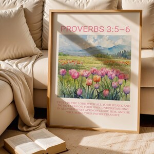 Pu&ograve; includere: Stampa artistica incorniciata con un paesaggio ad acquerello di tulipani rosa e arancioni. La stampa include il testo "PROVERBI 3:5-6" e un versetto biblico. L'opera d'arte &egrave; esposta vicino a un libro aperto e a un divano beige.