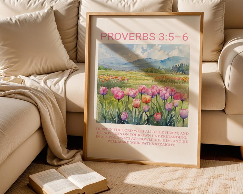 Pu&ograve; includere: Stampa artistica incorniciata con un paesaggio ad acquerello di tulipani rosa e arancioni. La stampa include il testo "PROVERBI 3:5-6" e un versetto biblico. L'opera d'arte &egrave; esposta vicino a un libro aperto e a un divano beige.