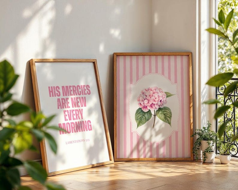 Pu&ograve; includere: Due stampe artistiche incorniciate. Una presenta un testo rosa che recita "HIS MERCIES ARE NEW EVERY MORNING" su sfondo bianco. L'altra ha uno sfondo a righe rosa con un'illustrazione di fiori di ortensia rosa.
