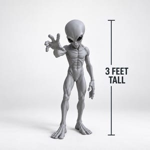 May include: A grey alien figurine with a large head, dark almond-shaped eyes, and a slender, muscular build. The figure stands with one arm extended forward and the other at its side. A vertical line graphic indicates the height is 3 FEET TALL.