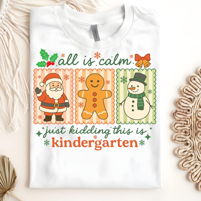 K&ouml;nnte beinhalten: Wei&szlig;es T-Shirt mit einem weihnachtlichen Motiv. Das Design zeigt den Weihnachtsmann, einen Lebkuchenmann und einen Schneemann, jeweils in einem dekorativen Rahmen. Der Text lautet "all is calm" und "just kidding this is kindergarten".