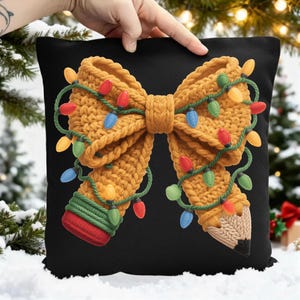 May include: Black decorative pillow featuring a knitted bow design with colorful Christmas lights. The bow is a warm yellow color, and the lights are red, blue, green, and yellow. The pillow is a festive holiday home decor item.