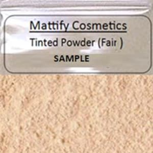 May include: A sample of Mattify Cosmetics tinted powder in Fair. The powder is a light beige color and is contained in a clear plastic bag. The text "SAMPLE" is printed below the product name.