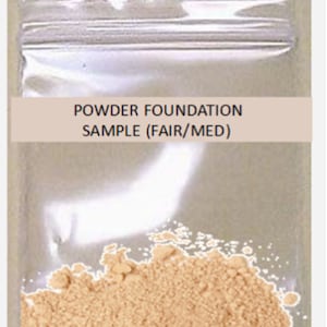 May include: A sample of powder foundation in a clear, sealed plastic bag. The text "POWDER FOUNDATION SAMPLE (FAIR/MED)" is printed on a light brown label. The foundation is a light beige color and appears finely milled.