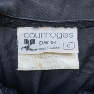 May include: Close-up of a black garment with a white label. The label reads "courr&egrave;ges paris made in france" with a logo. The label also lists the fabric composition: 83% Wool and 17% Polyamide/Nylon.