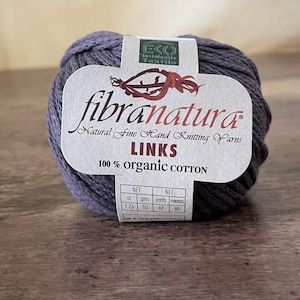 May include: A ball of dark gray yarn with a label that reads "fibranatura LINKS 100% organic cotton." The label also includes the weight of the yarn: 1.76 oz, 50 gms, 87 yards, and 80 meters. The yarn is on a wooden surface.