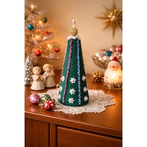 May include: A cone-shaped Christmas tree decoration made of dark green felt, adorned with vertical rows of blue and purple sequins, small white flower appliqués, and white pearl beads. A gold filigree sphere sits at the very top.